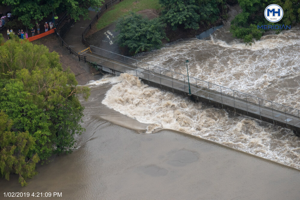Crowd gathered to watch water spill over Aplins Weir, aerial photograph during floods, Mundingburra, 2019. 