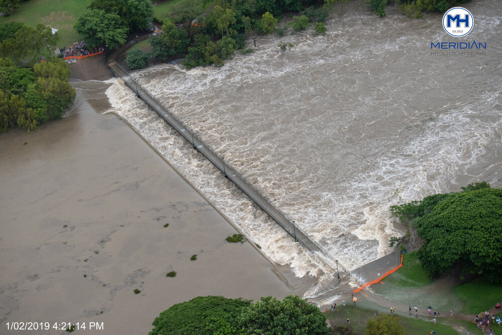 Crowd gathered to watch water spill over Aplins Weir, aerial photograph during floods, 2019