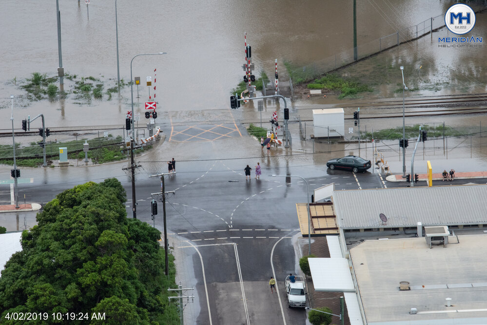 People gather around Oonoonba Road intersection to watch flood waters, 2019. 