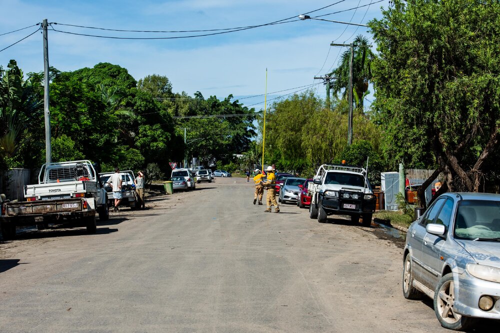 Ergon Energy workers walking down previously flooded street, Hermit Park, 2019