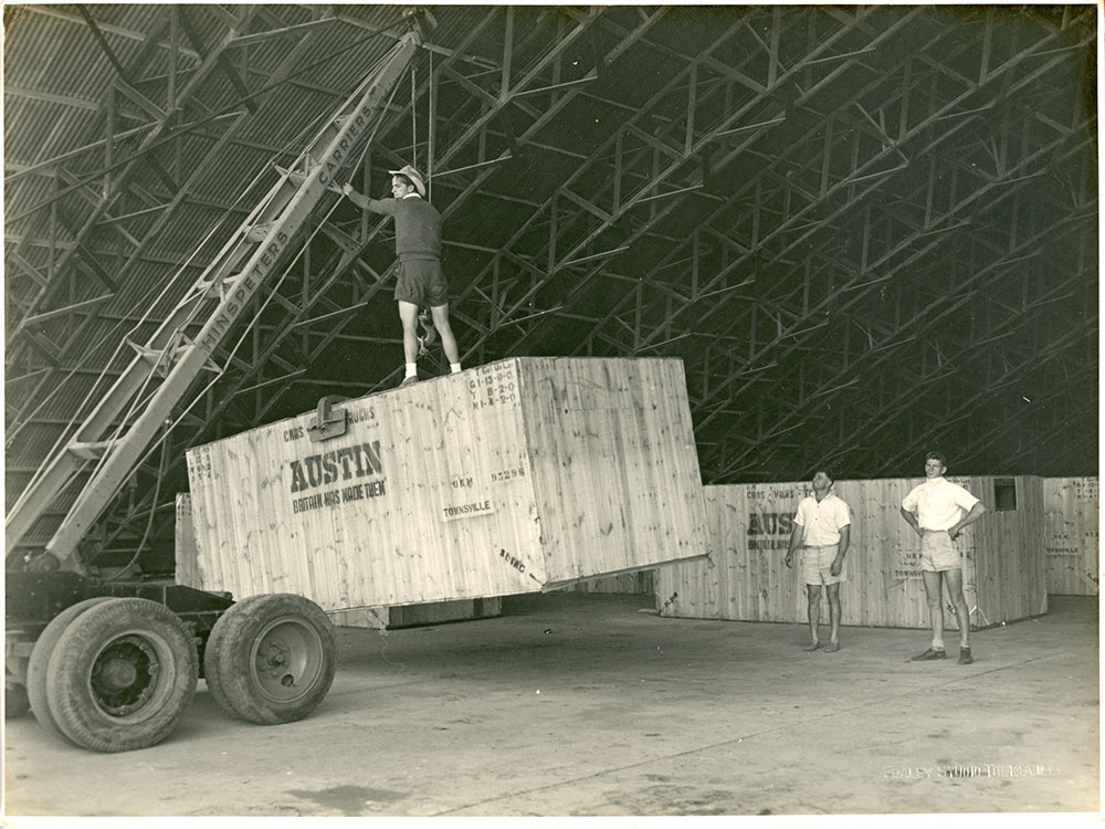 McDonald collection : Austin A70 Somerset cars imported by McDonald Brothers being unloaded for assembly in the hangar at Mount Louisa, Townsville, ca.1953
