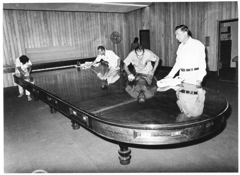 The Mayor, Alderman Max Hooper, inspects restoration work on the Council table after its installation in the new Administration Centre, Townsville, 12th January, 1976. 