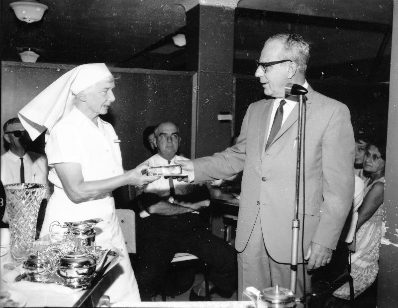 Chairman of the Townsville Hospital Board, Mr F.J. Henderson presents Sister R. Baines with a gift, on her retirement from the Townsville General Hospital. 