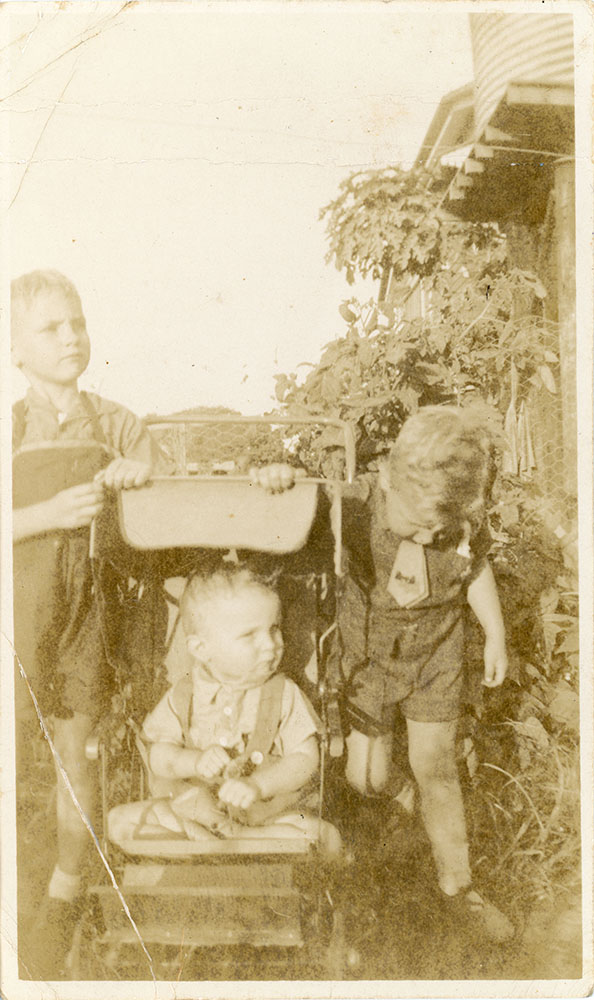 Two young boys with a baby in a pram posing for a photograph