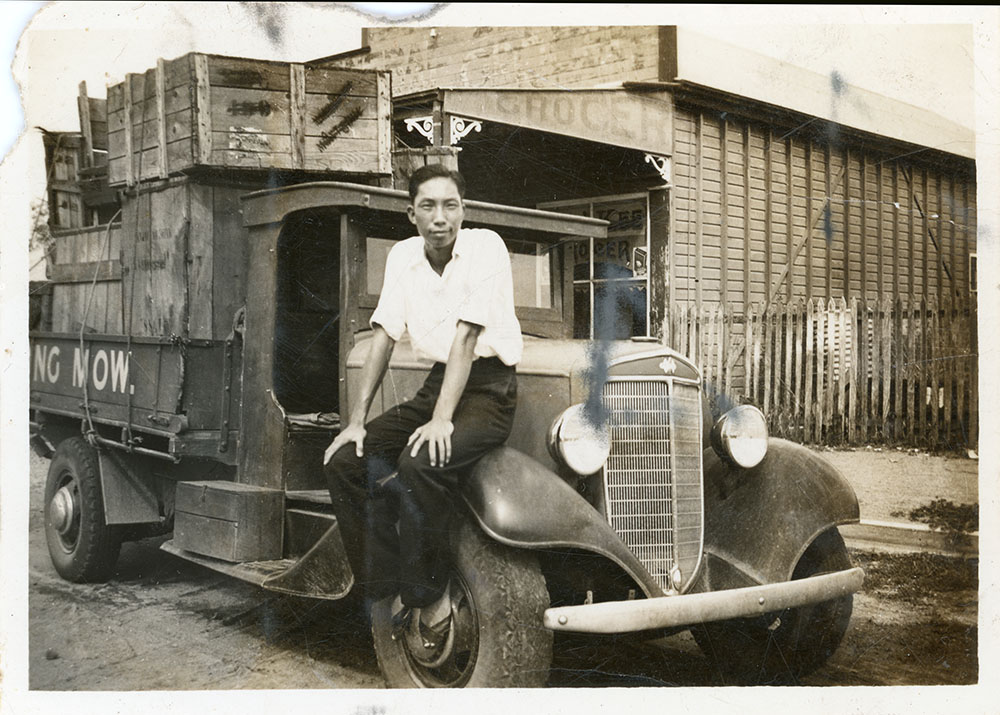 Philip Leong sitting on a truck, Townsville, 1940's