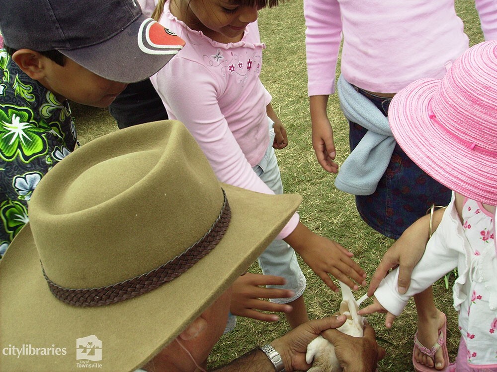 Children patting a pigeon at Cultural Fest, Strand Park, Townsville, 19 August 2007
