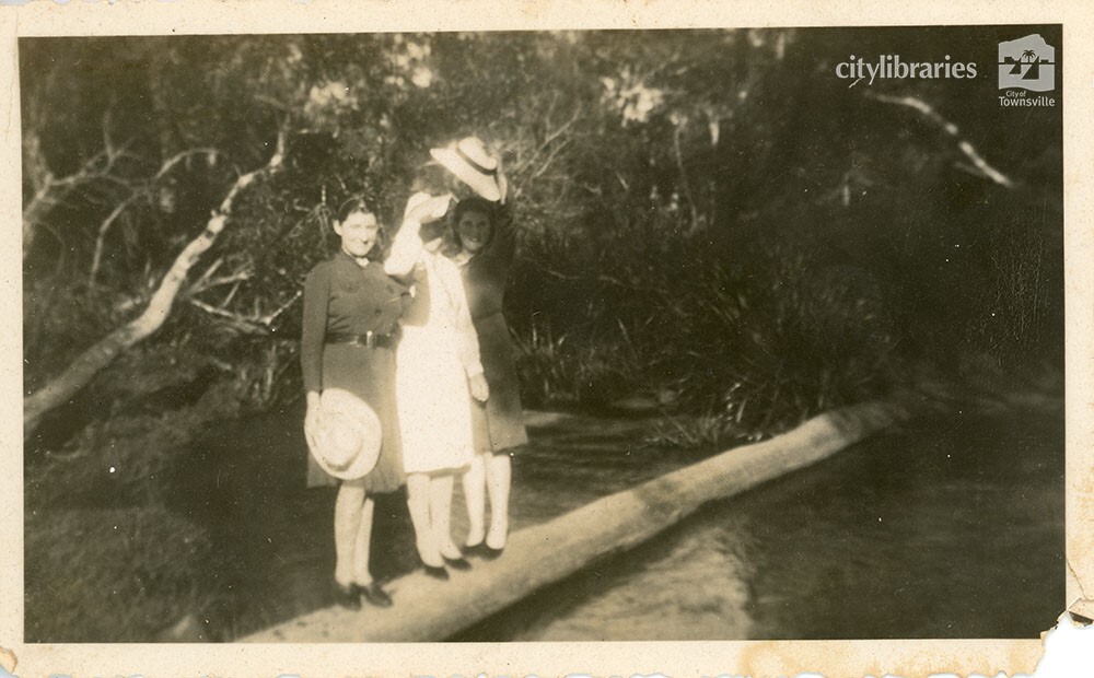 Group posing on a log over the water, 1940
