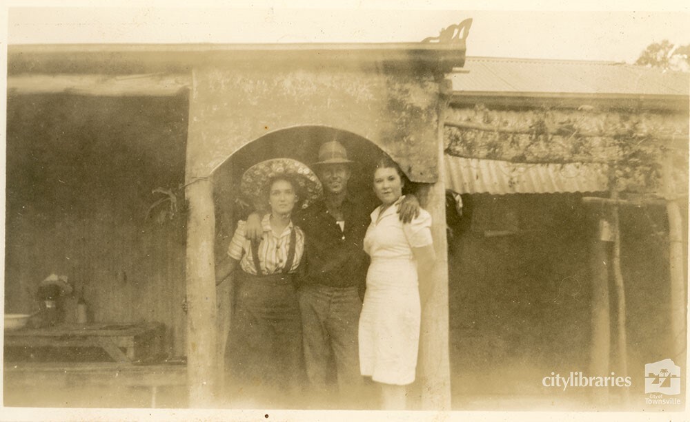 Three people in front of a structure, December 1939