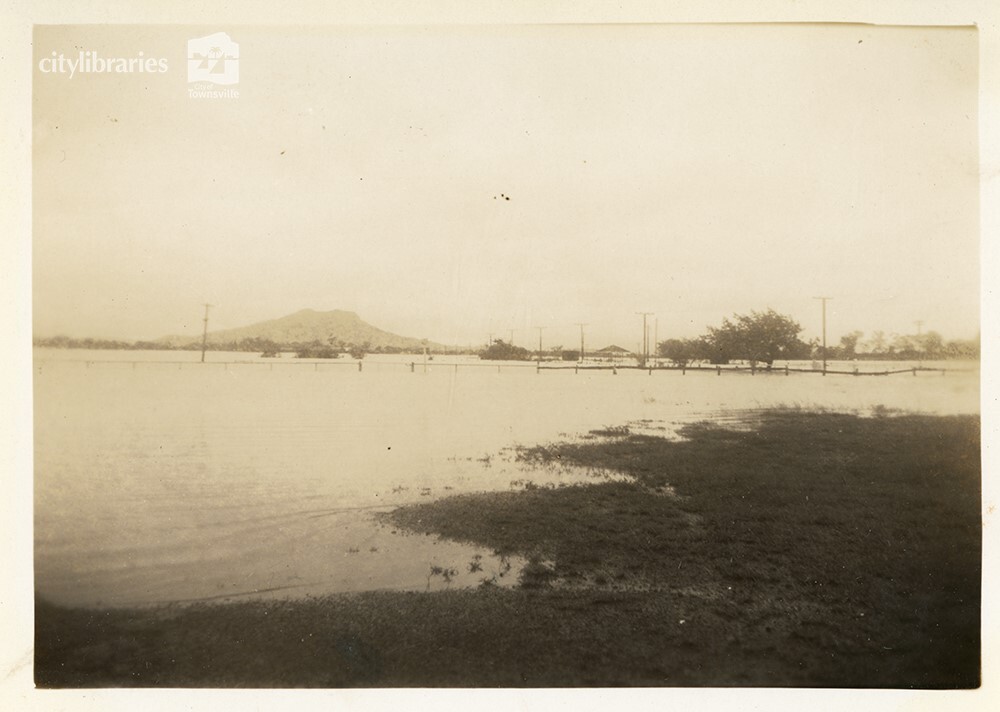 Cluden racecourse yard during flood, with Cluden station and Castle Hill, Townsville [10 February 1946]