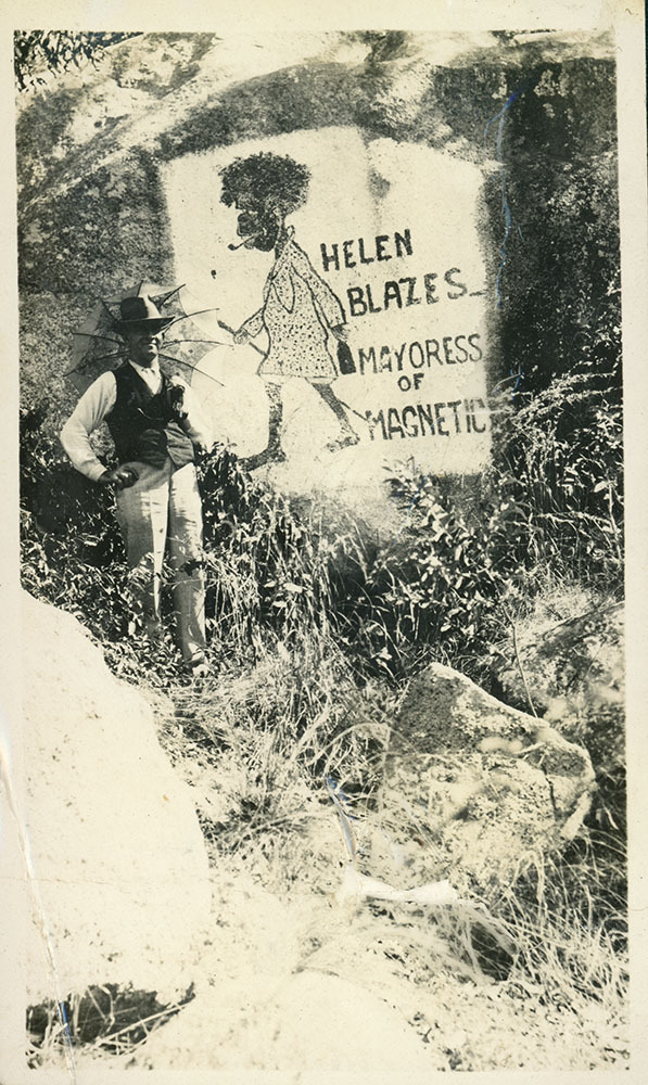 Arthur (Doug) Armstrong standing by artwork on a rock, Helen Blazes, Mayoress of Magnetic, Magnetic Island, [between 1908 and 1930].