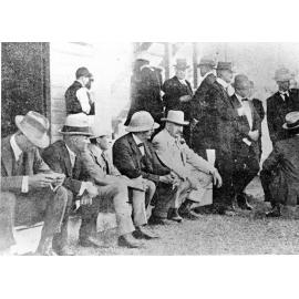 Mr Tom Lowth, sitting amongst a group of men at Cluden Racecourse, Townsville. 