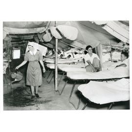 A nursing sister watering the earth floor at the 2/14th field hospital at Pallarenda