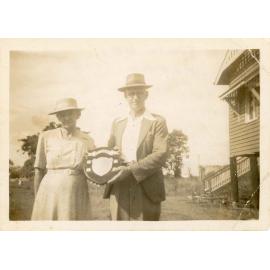 Mr. Charlie Chase, headmaster of the Oonoonba School, and Mrs Chase holding the shield won on sports day, ca.1953