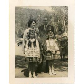 Harold Holt, Minister for Immigration and Mrs Zara Holt pose with children dressed in their national costumes during a visit the Stuart Immigration Holding Centre, Townsville, ca.1952