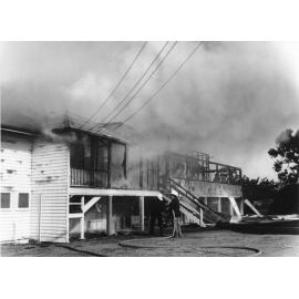 Firemen hosing down the fire damaged remains of the Queensland Department of Primary Industries Animal Research Station, Oonoonba, Townsville. 
