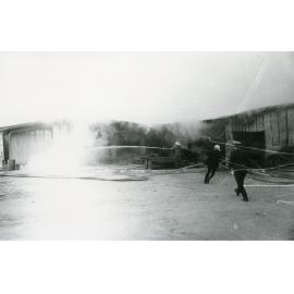 Firefighters attending the fire at the Endeavour Foundation workshop, Landsborough Street, North Ward, Townsville, 27th May, 1974