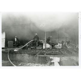 Firefighters attending the fire at the Endeavour Foundation workshop, Landsborough Street, North Ward, Townsville, 27th May, 1974