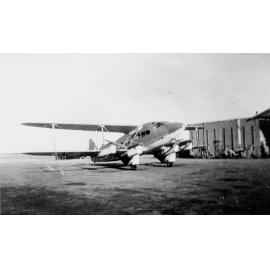 De Havilland DH86 transport aircraft in front of hangar, ca 1940 
