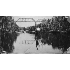 Paddy Neville on Reid River, with bridge in background, 1926 
