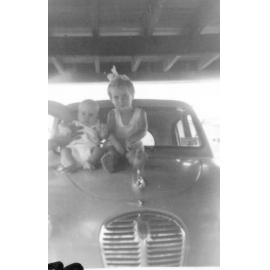 Leanne and John McIntosh sitting on bonnet of car, Aitkenvale, 1963 