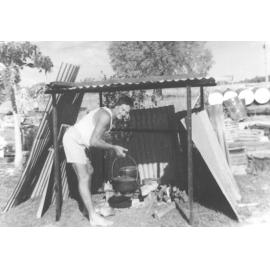 Jim Armstrong cooking Christmas dinner on makeshift kitchen after Cyclone Althea, 1971 