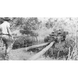 Joe Brabon and Archie Taylor laying logs across a creek to build a bridge, 1952 