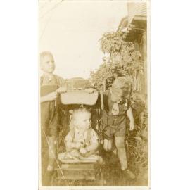 Two young boys with a baby in a pram posing for a photograph