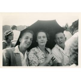 Family photograph from the Quelch Forno collection : A woman and two men posing for a photograph under an umbrella