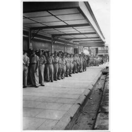 Troops lined up for a beer at a wet canteen in Blackwood Street, Townsville, 9 February 1944
