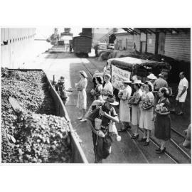 Members of the Townsville Branch of the Australian Comforts Fund distributing bags of fruit to soldiers of the 5th Australian Division as they disembark from HMT Katoomba on the 25th March 1945
