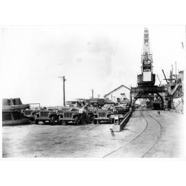Vehicles of the 1st Australian Army Transport on the Townsville wharf, ready to be loaded aboard the Liberty ship, SS James Oliver for shipment to Lae, New Guinea, 18 October 1944