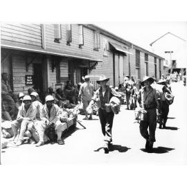 Members of the 24th Aust. Inf. Bde. walk past American troops on the Townsville wharf 28/1/44