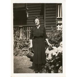 Unidentified woman in a dark dress standing in a garden