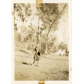 Family photograph from the Quelch Forno collection : Beryl Forno posing for a photograph in a Girl Guides uniform in front of a Union Jack flag at the Burdekin Downs Guide Camp, 1948