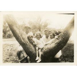 Family photograph from the Quelch Forno collection : Four adults and one child posing near a tree for a photograph