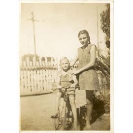 Family photograph from the Quelch Forno collection : Girl posing with a boy on a tricycle
