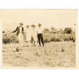 Family photograph from the Quelch Forno collection : Two men and two women posing for a photograph with a pineapple plantation in the background