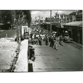 Procession of people following a brass band in Flinders Street after the peace announcement, Townsville, 15 August 1945
