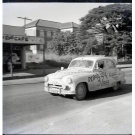 Car 37 in the Redex Trial 1955 on Ingham Road, Townsville. West End Primary School and the Golden Gate cafe are in the background