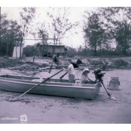 Russell at the oars, Bruce with the hat, the hut in the background and the Victa Mower outboard, Ocean Creek, Ayr, ca. 1963