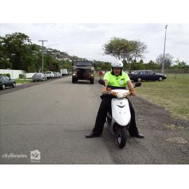 Volunteer marshall in front of army vehicle in the Tropigo Carnival parade at Cultural Fest, The Strand, Townsville, 18 August 2007