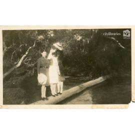 Group posing on a log over the water, 1940