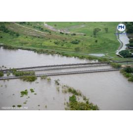People gather on riverbank to watch water level skirt under Rooney's Bridge, aerial photograph during floods, 2019. 