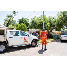 SES Volunteer standing beside vehicle in flood affected street with damaged goods stacked on footpath, Hermit Park, 2019