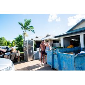 Residents standing in front of flood affected home with skip bin located on driveway, Idalia, 2019